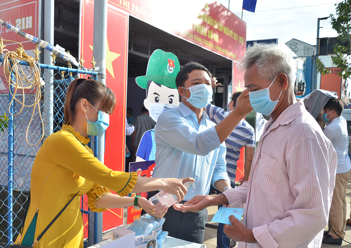 Cử tri đến các khu vực bỏ phiếu số 6, khu phố Vĩnh Đông 2, thị trấn Vĩnh Thuận (Vĩnh Thuận) được kiểm tra thân nhiệt, sát khuẩn tay để phòng, chống dịch bệnh COVID-19. Ảnh: MI NI